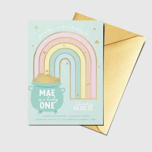 May include: A light blue invitation with a rainbow and a pot of gold. The text reads "MAE is a lucky ONE" and "Saturday 03.02.25".