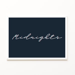 May include: A framed print with the word "Midnights" in a white, cursive font. The text has a 3D effect with red and blue outlines, set against a dark blue background. The frame is white.