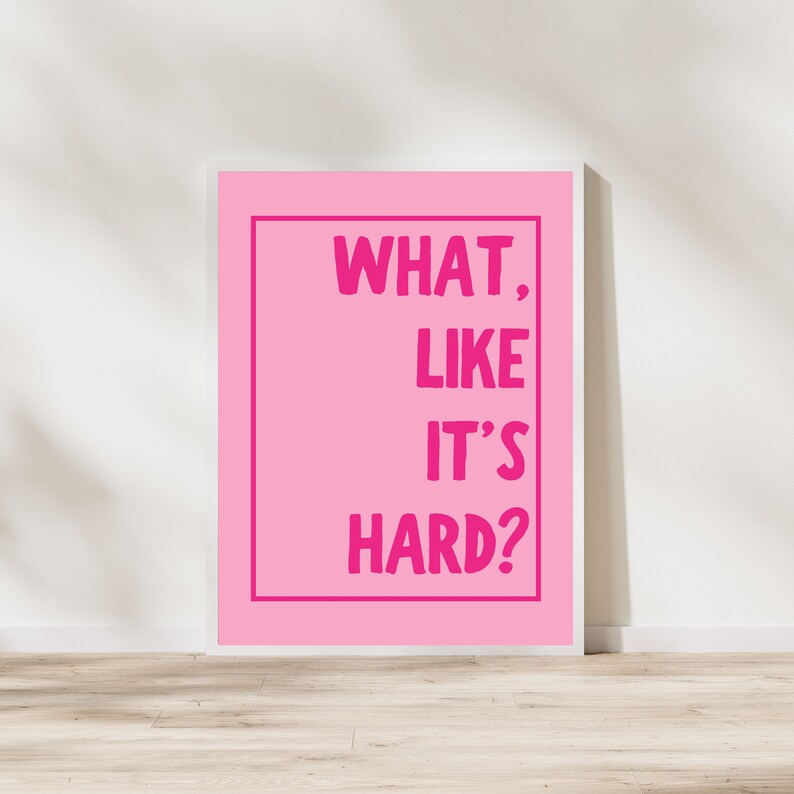Może przedstawiać: R&oacute;żowa drukowalna grafika ścienna w białej ramie. Tekst na wydruku brzmi "WHAT, LIKE IT'S HARD?"