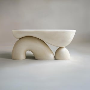 May include: A white, organic-shaped coffee table with a curved top and three rounded legs. The table is made of a smooth, white material.