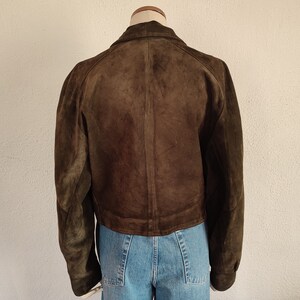 Puede incluir: Una chaqueta de ante marr&oacute;n con cierre de cremallera. La chaqueta est&aacute; en un maniqu&iacute; y tiene un estilo recortado.
