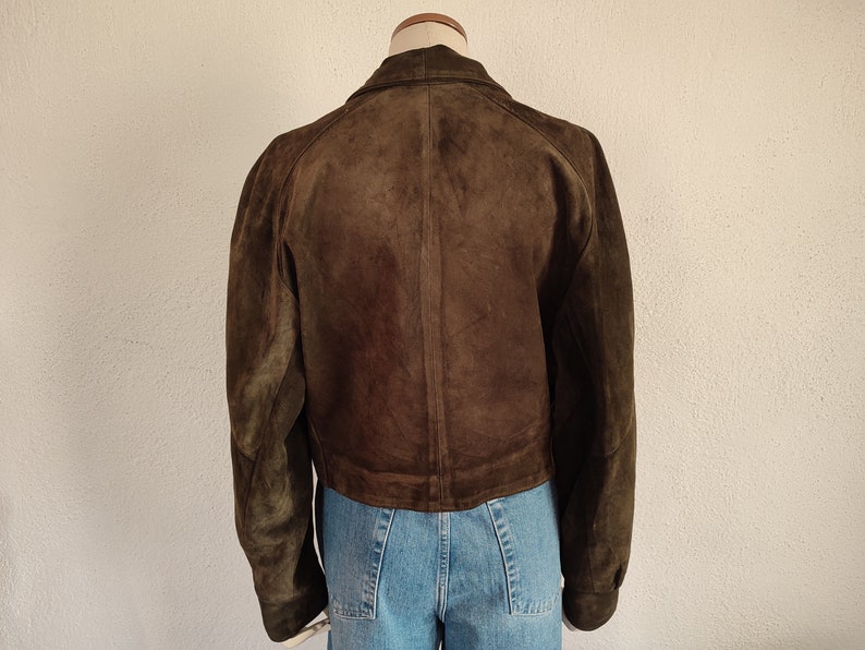 Puede incluir: Una chaqueta de ante marr&oacute;n con cierre de cremallera. La chaqueta est&aacute; en un maniqu&iacute; y tiene un estilo recortado.