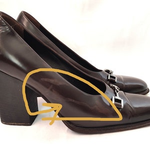 May include: A pair of brown leather pumps with a chunky heel and silver buckle accents.
