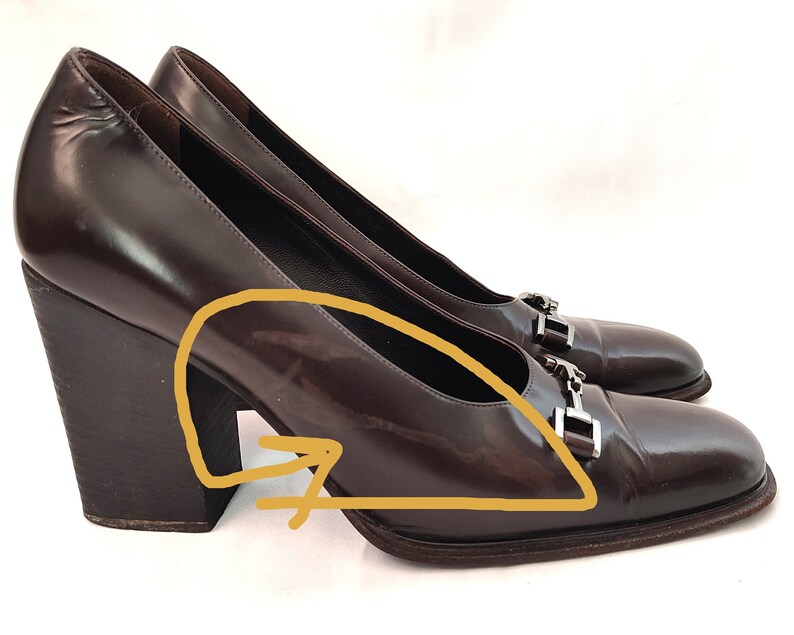 May include: A pair of brown leather pumps with a chunky heel and silver buckle accents.