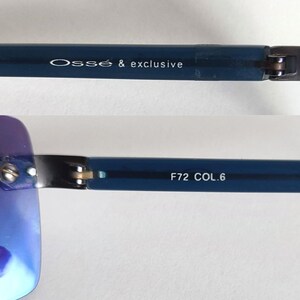 May include: Close-up of blue-framed sunglasses. The text "Oss&eacute; & exclusive" is printed on the temple. The other temple has the text "F72 COL.6". The lenses have a gradient blue hue.