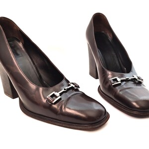 May include: A pair of brown leather heeled pumps with a silver buckle detail.
