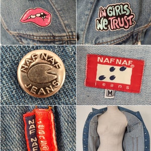 Pu&ograve; includere: Una giacca di jeans blu chiaro con un bottone in metallo dorato che dice "NAF NAF JEANS". La giacca ha una toppa rossa che dice "NAF NAF jeans" e una taglia "M". Ci sono due toppe sulla giacca, una con una bocca rosa e l'altra con il testo "in girls we trust".