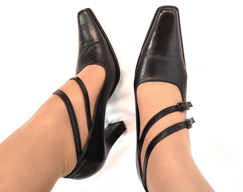 May include: A pair of black leather heeled shoes with ankle straps and buckles.