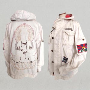 May include: A white hooded jacket with embroidered details on the back. The jacket has a zipper closure, two pockets, and a patch on the sleeve that says "Castle Rock".