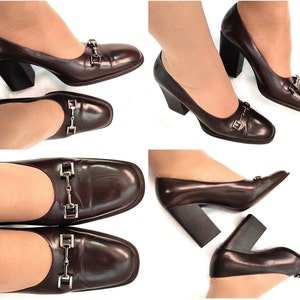 May include: Brown leather pumps with a chunky heel and a silver buckle detail. The shoes have a square toe and are shown on a white background.