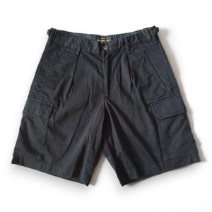 May include: Dark navy cargo shorts with multiple pockets and a button closure. The shorts have a pleated front and a classic, casual design. The shorts are made of a durable fabric and are suitable for outdoor activities.