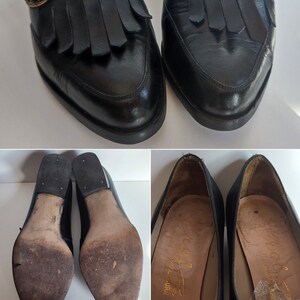 May include: Black leather loafers with fringe detailing and gold-tone buckles. The shoes have a classic design with a rounded toe and a low heel. The soles show wear, indicating they are pre-owned.