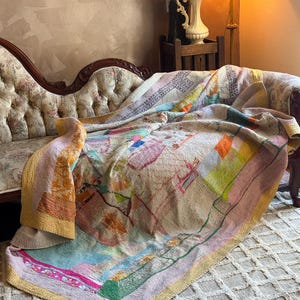 May include: A rectangular kantha quilt featuring a patchwork of various fabric scraps in muted tones of yellow, pink, blue, and green. The textile displays intricate running stitch patterns throughout, with visible seams connecting diverse patterned and solid fabric pieces.