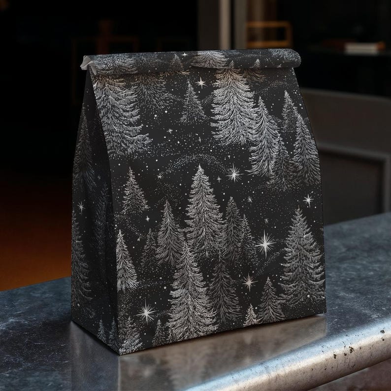 Pu&ograve; includere: Un sacchetto regalo di carta nera con un motivo ripetuto di pini bianchi e stelle. Il sacchetto &egrave; piegato in alto e poggia su una superficie metallica. Il design evoca una scena di foresta invernale.