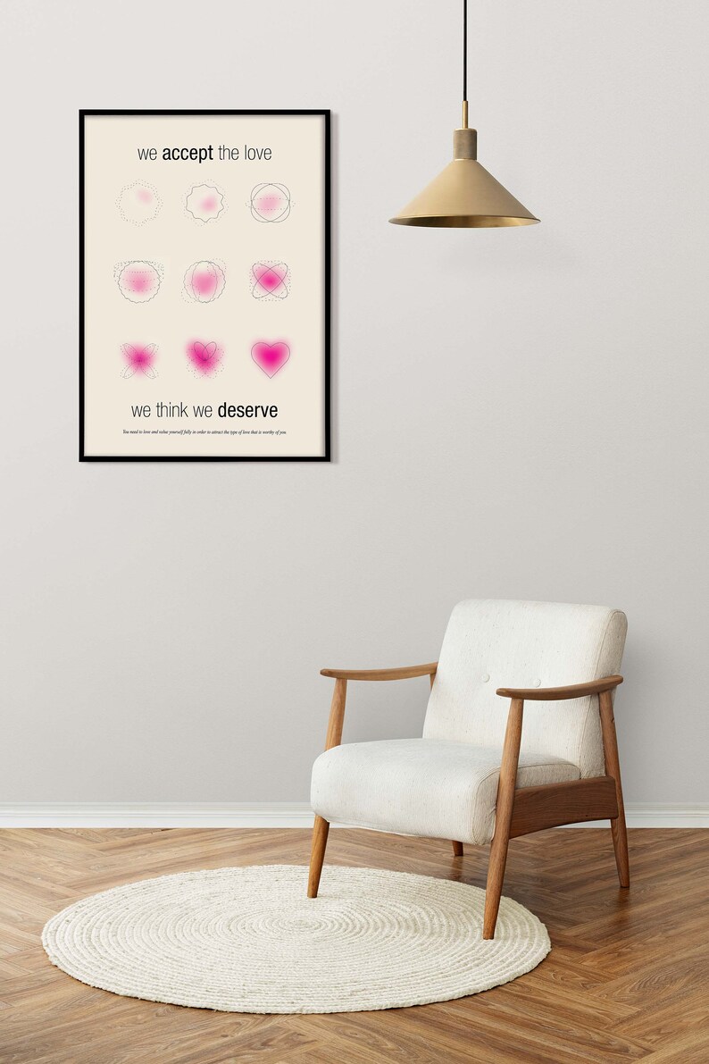 May include: A framed art print with the text "we accept the love" and "we think we deserve". The artwork features pink abstract shapes. A white chair and a round rug are in the foreground.
