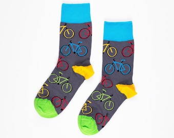 May include: A pair of gray socks with a colorful bicycle pattern. The socks have a blue cuff and a yellow heel and toe.