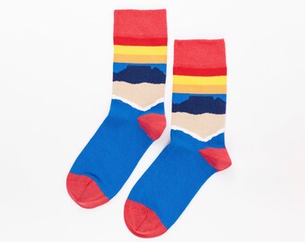 May include: A pair of blue socks with red, yellow, and blue stripes and a mountain scene design.