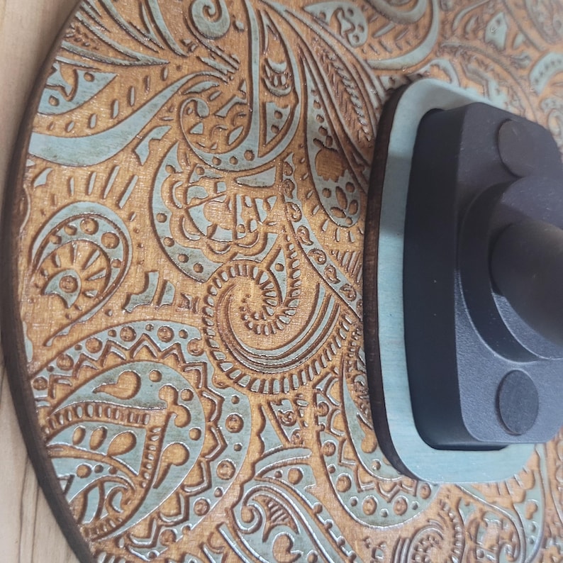 Extreme close-up of the laser-engraved wood grain, highlighting the detailed paisley swirls and the vintage turquoise paint wash in the recessed areas.