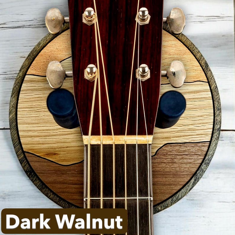 Acoustic guitar headstock on dark walnut wood wall mount guitar hanger with round layered hardwood backplate and padded arms