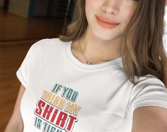 May include: White t-shirt with the text "IF YOU THINK MY SHIRT IS TIGHT" in a retro font. The text is in red, yellow, and blue. The shirt is being worn by a person.