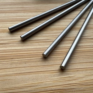 Könnte beinhalten: Vier silberne Metallstäbe, die auf einer Holzoberfläche fächerförmig angeordnet sind.