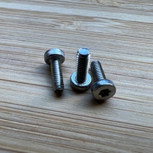 Może przedstawiać: Trzy srebrne śruby z gwiazdą.