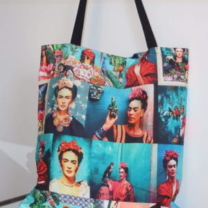 Könnte beinhalten: Eine große Tragetasche mit schwarzen Henkeln und einem bunten Druck des Porträts von Frida Kahlo. Der Druck zeigt mehrere Bilder von Frida Kahlo in verschiedenen Posen und Outfits, mit einem Hintergrund aus Blumen, Vögeln und anderen Elementen.
