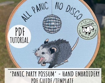 Peut inclure: Un motif de broderie à la main représentant un opossum avec le texte "All Panic No Disco" et une boule disco. Le motif est dans un cerceau de broderie en bois avec un fond bleu. Le texte "PDF Tutorial" est sur un cercle blanc dans le coin inférieur gauche. Le texte "The Artful Possum" est sur un cercle vert dans le coin supérieur droit.