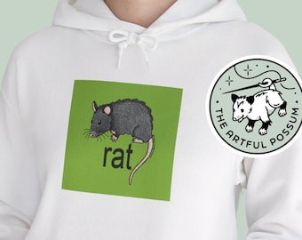 May include: White hoodie with a green square graphic featuring a black rat and the word "rat" in black text. The hoodie has a kangaroo pocket and a small circular patch with a white possum and the text "The Artful Possum".