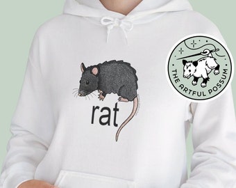 May include: White hoodie with a black rat illustration and the word "rat" printed on the front. The hoodie has a kangaroo pocket and a drawstring hood. A small circular sticker with a possum illustration and the text "The Artful Possum" is on the right sleeve.