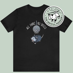 K&ouml;nnte beinhalten: Schwarzes T-Shirt mit einem wei&szlig;en Opossum-Motiv und dem Text "The Artful Possum". Das Shirt zeigt au&szlig;erdem ein wei&szlig;es Discokugel-Motiv und den Text "All Panic | No Disco".