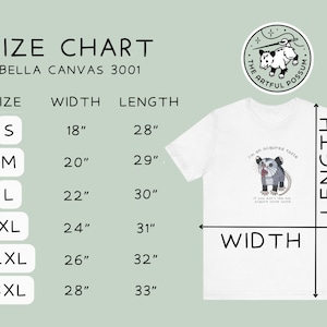 Op de afbeelding: Maattabel voor Bella Canvas 3001 T-shirts, met breedte- en lengtemaat in inches voor maten S tot en met 3XL. De tabel wordt weergegeven op een wit T-shirt met een afbeelding van een opossum en de tekst "I'm an acquired taste. If you don't like me, acquire some taste."