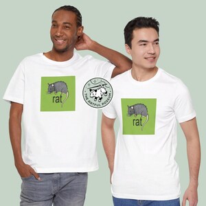 Puede incluir: Dos camisetas blancas con un gr&aacute;fico cuadrado verde que presenta una rata negra y la palabra "rat" impresa en negro. Una camiseta tambi&eacute;n tiene un gr&aacute;fico circular de una zarig&uuml;eya con el texto "The Artful Possum".