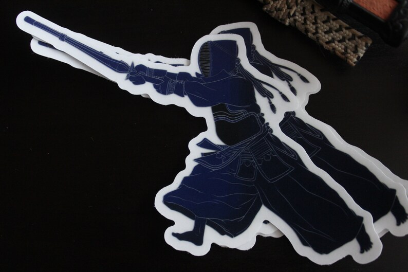 May include: A blue and white sticker of a person wearing a kendo uniform holding a shinai, a bamboo sword used in kendo.
