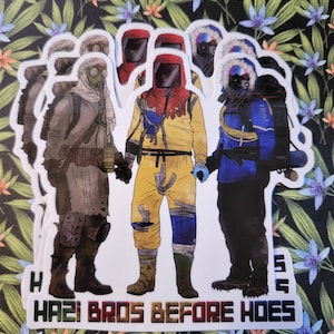 Op de afbeelding: Vier cartoonfiguren die verschillende beschermende pakken dragen en elkaar vasthouden. De tekst "HAZI BROS BEFORE HOES" is onder de figuren gedrukt.
