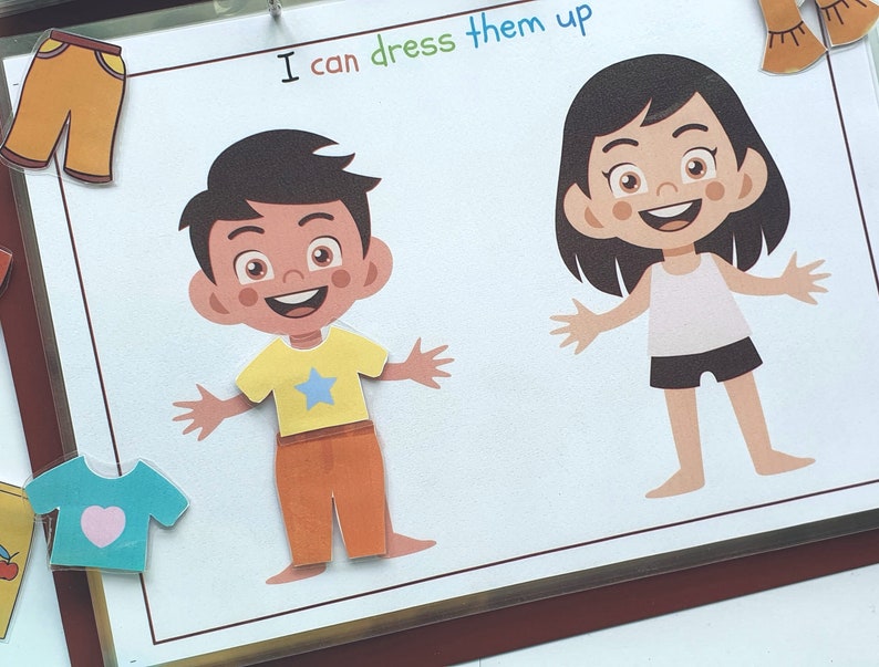May include: A printable activity sheet with two cartoon characters, a boy and a girl, with the text "I can dress them up".