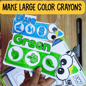 May include: A set of colorful, large crayon-shaped cards with the words "Blue", "Green", and "Make Large Color Crayons" printed on them. Each card features a cartoon eye and various images related to the color, such as a butterfly, whale, and leaf.