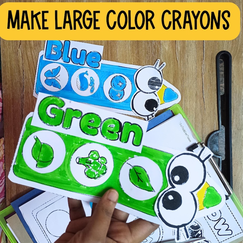 May include: A set of colorful, large crayon-shaped cards with the words "Blue", "Green", and "Make Large Color Crayons" printed on them. Each card features a cartoon eye and various images related to the color, such as a butterfly, whale, and leaf.