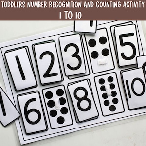 Puede incluir: Cartas de números en blanco y negro con puntos negros correspondientes para contar del 1 al 10. Las cartas están dispuestas sobre una superficie blanca. El título "Toddlers Number Recognition and Counting Activity 1 to 10" está en la parte superior de la imagen.