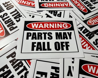 May include: A stack of white warning signs with black and red text. The sign reads "WARNING PARTS MAY FALL OFF".