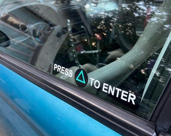May include: A bright blue car door featuring a white decal on the window that reads PRESS with a teal triangle icon followed by TO ENTER. The interior of the vehicle is visible through the glass, showing a dashboard, steering wheel, and gauges.