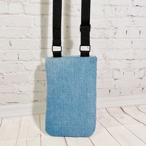 crossbody tasche umhängetasche aus hellblauer upcycling jeans, smartphonetasche zum umhängen, rückseite stehend