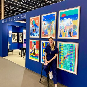May include: A display wall labeled FRAMES & DESIGN featuring five framed colorful art prints with illustrations of people, landscapes, and a swimming pool. The prints are arranged on a deep blue wall, showcasing various vibrant scenes and graphic styles.