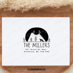 May include: A black and white illustration of a mountain range with a fox silhouette in front of a crescent moon. The text "THE MILLERS" is below the image, followed by the address "321 Grant Mc Way, Richmond, BC V7B 0A4". The text "@stampbooth" is at the bottom of the image.