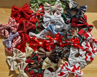 May include: A collection of fabric bows in various patterns and colours, including red, green, white, gold, and blue. The bows feature diverse prints such as snowflakes, holiday themes, plaid, polka dots, and geometric shapes, arranged in a circular cluster.