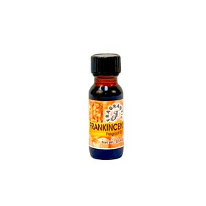 May include: A small, dark glass bottle with a black cap, containing a dark amber liquid. The label reads "Frankincense Fragrant Oil" with a net weight of 0.5 fl oz. The label has a yellow and orange background with the brand name.