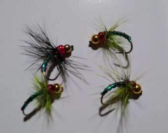 May include: Four fly fishing lures with green and red beads and green and gold beads. The lures have green and black feathers.