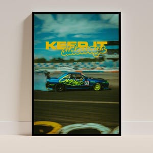 Könnte beinhalten: Ein blaues Auto mit dem Wort "CHARGED" auf der Seite driftet auf einer Rennstrecke. Das Auto ist in Bewegung und der Hintergrund ist verschwommen. Der Text "KEEP IT SIDEWAYS" ist in gelben Buchstaben oben im Bild geschrieben.