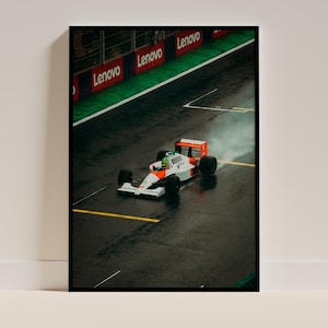 May include: A white and orange Formula One race car driving on a wet track. The car is leaving a trail of water behind it. The track is lined with green grass and red and white Lenovo signs.