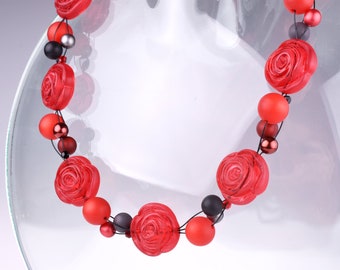 Große Statementkette mit Perlen in Rosenform, hellrote Blumenperlen verflochten mit Polarisperlen und Glasperlen auf schwarzen Fäden